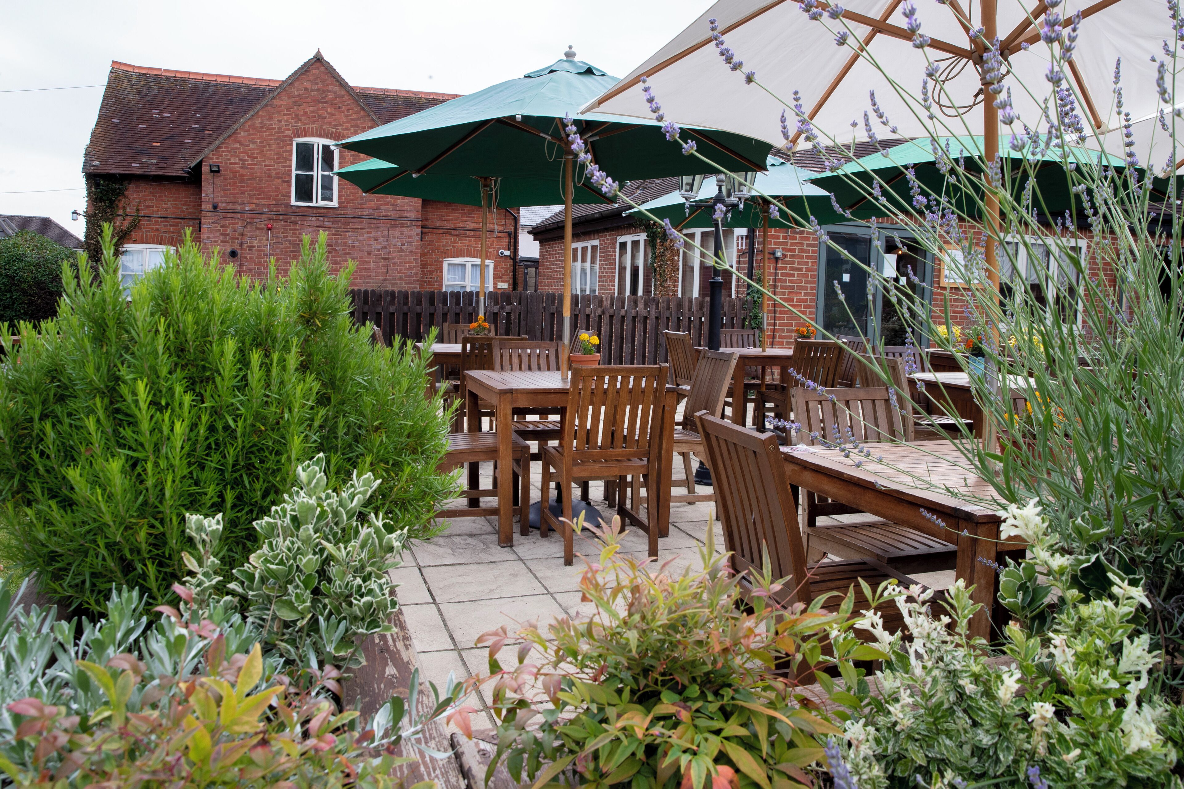 An outdoor patio with wooden furniture and green umbrellas.