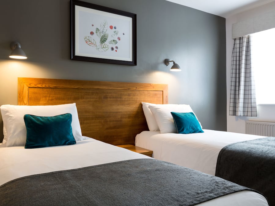 Una habitación de hotel con dos camas, cabecero de madera y un cuadro en la pared.