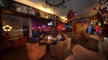 A bar area with sofas and a pool table, decorated with skulls and pirate-themed items.