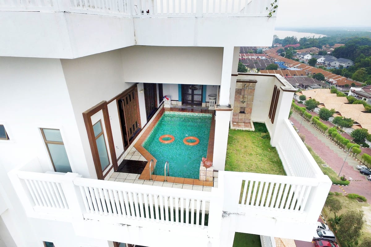 Un edificio residencial con piscina en la azotea, un balcón y vistas a una zona residencial.