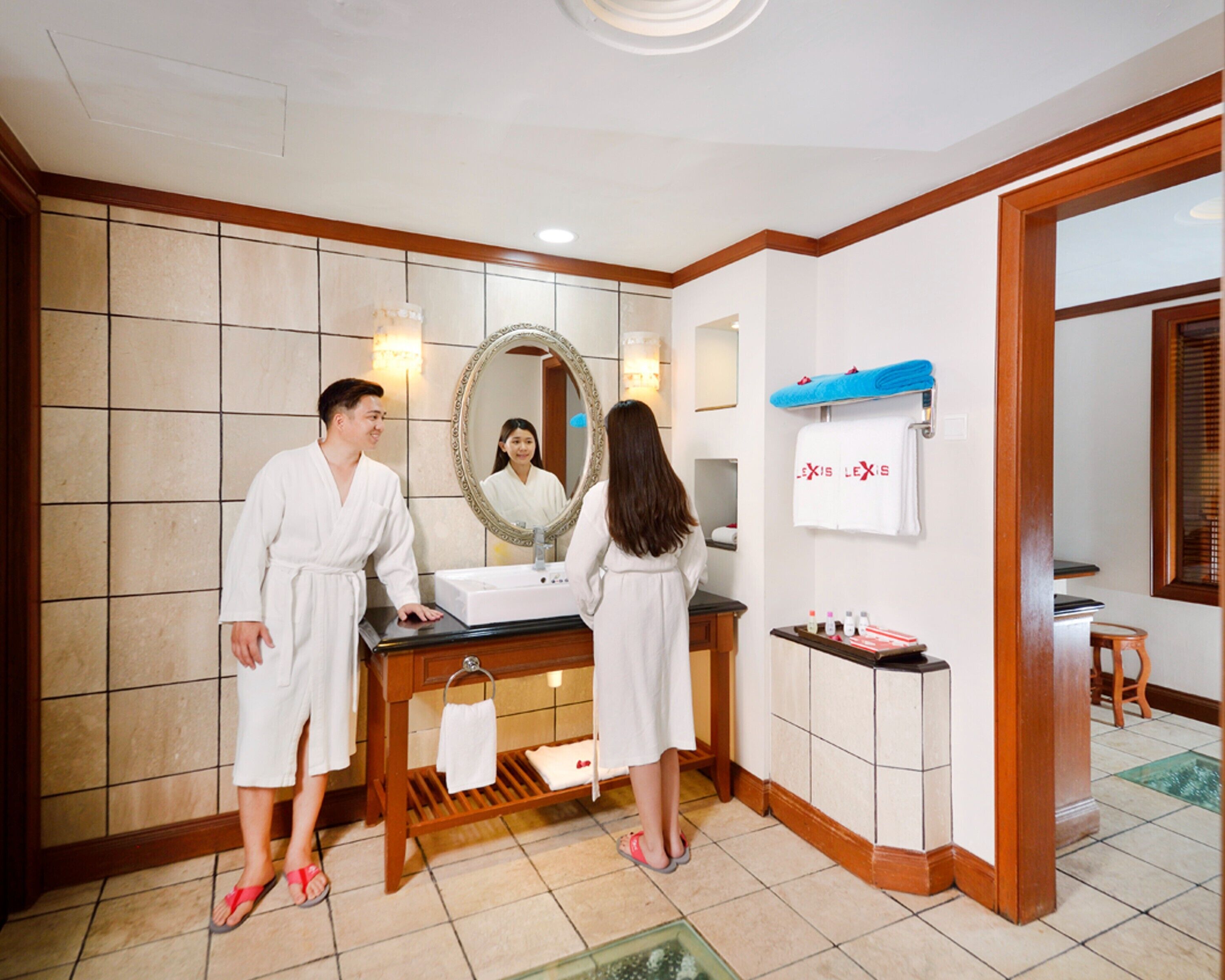 Un baño de hotel con un espejo grande, un lavabo y tocador. Hay toallas y artículos de aseo en la encimera.