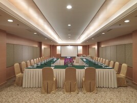 Un salón de conferencias con una larga mesa, sillas y una pantalla de proyector.