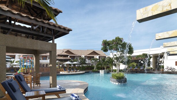 A pool area with lounge chairs, a water play structure, and a fountain.