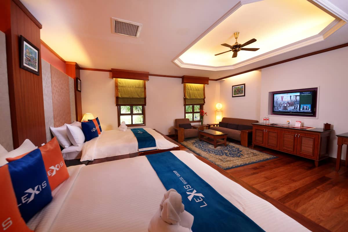 Una habitación de hotel con dos camas, un sofá, un televisor y un ventilador de techo.