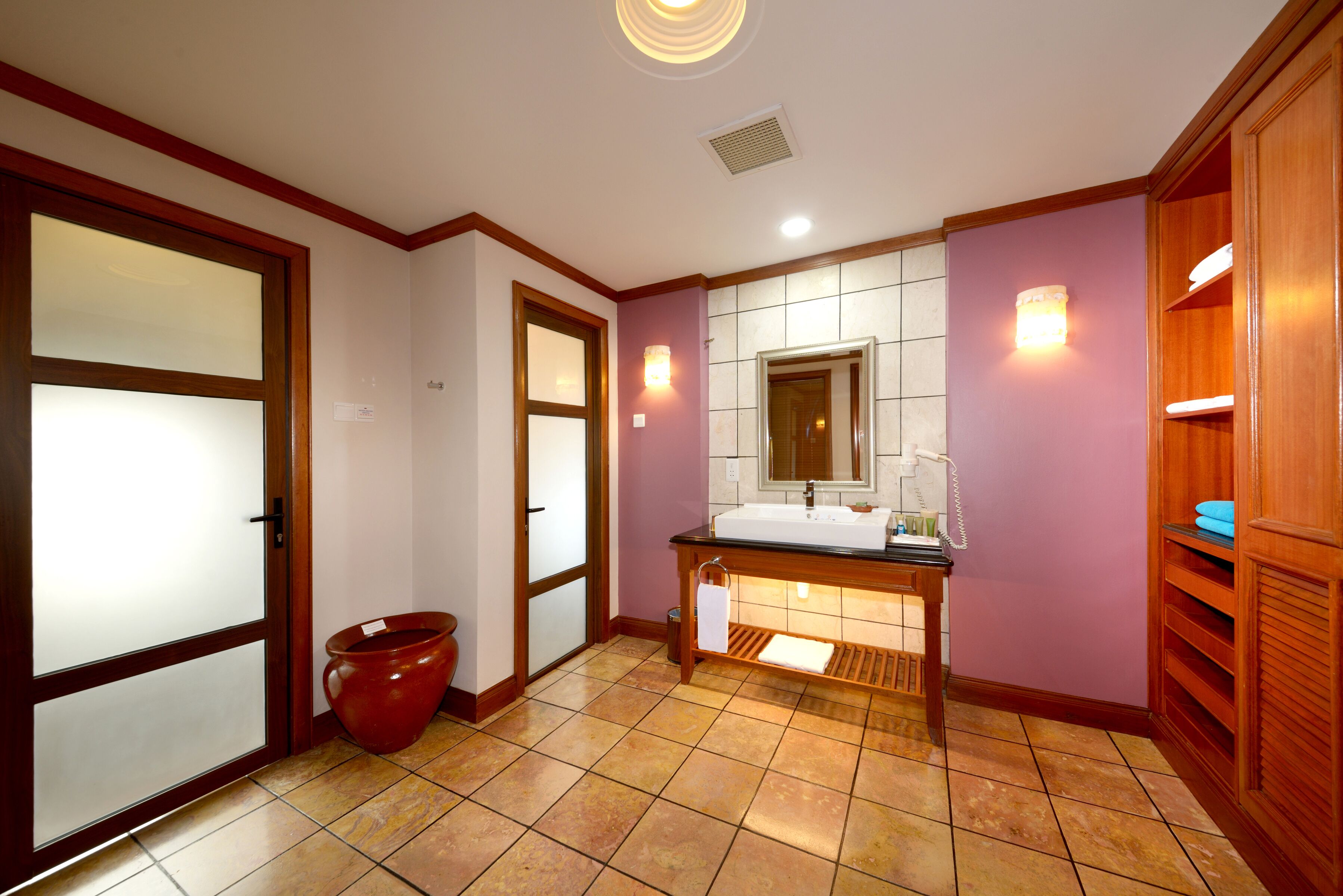 A bathroom with a wooden vanity, a large mirror, and a tiled floor.