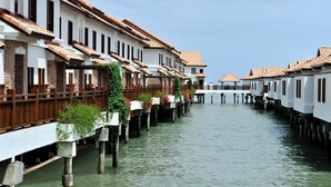 A canal-side building with multiple levels, wooden railings, and potted plants.