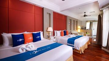 A hotel room with two beds, red padded headboards, white bedding, and a blue and white logo on the beds.
