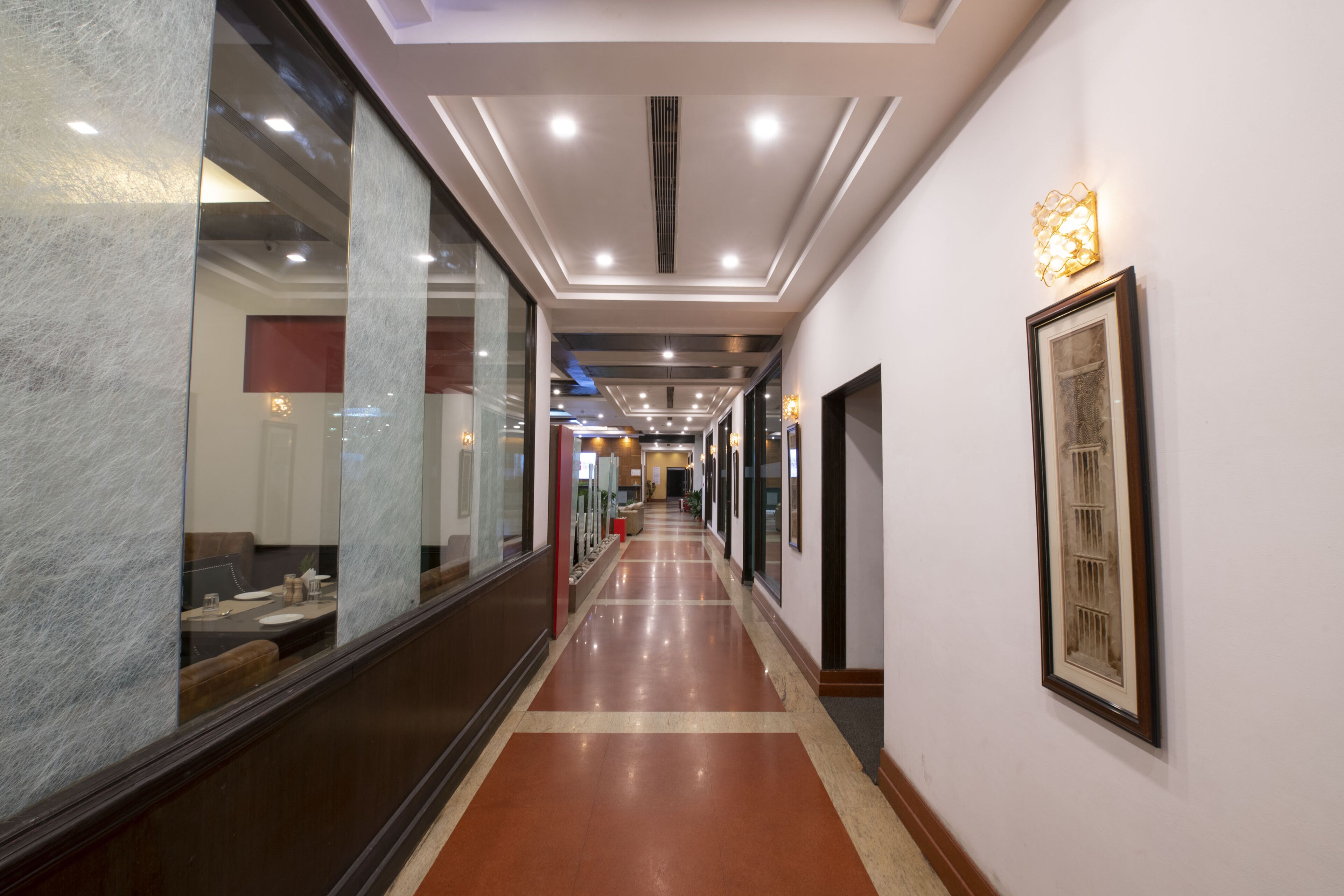A hallway with a polished floor, framed artwork on the walls, and recessed lighting.