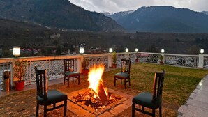 A fire pit with chairs in a mountainous outdoor setting. - Mastiff Grand Manali (Manali)