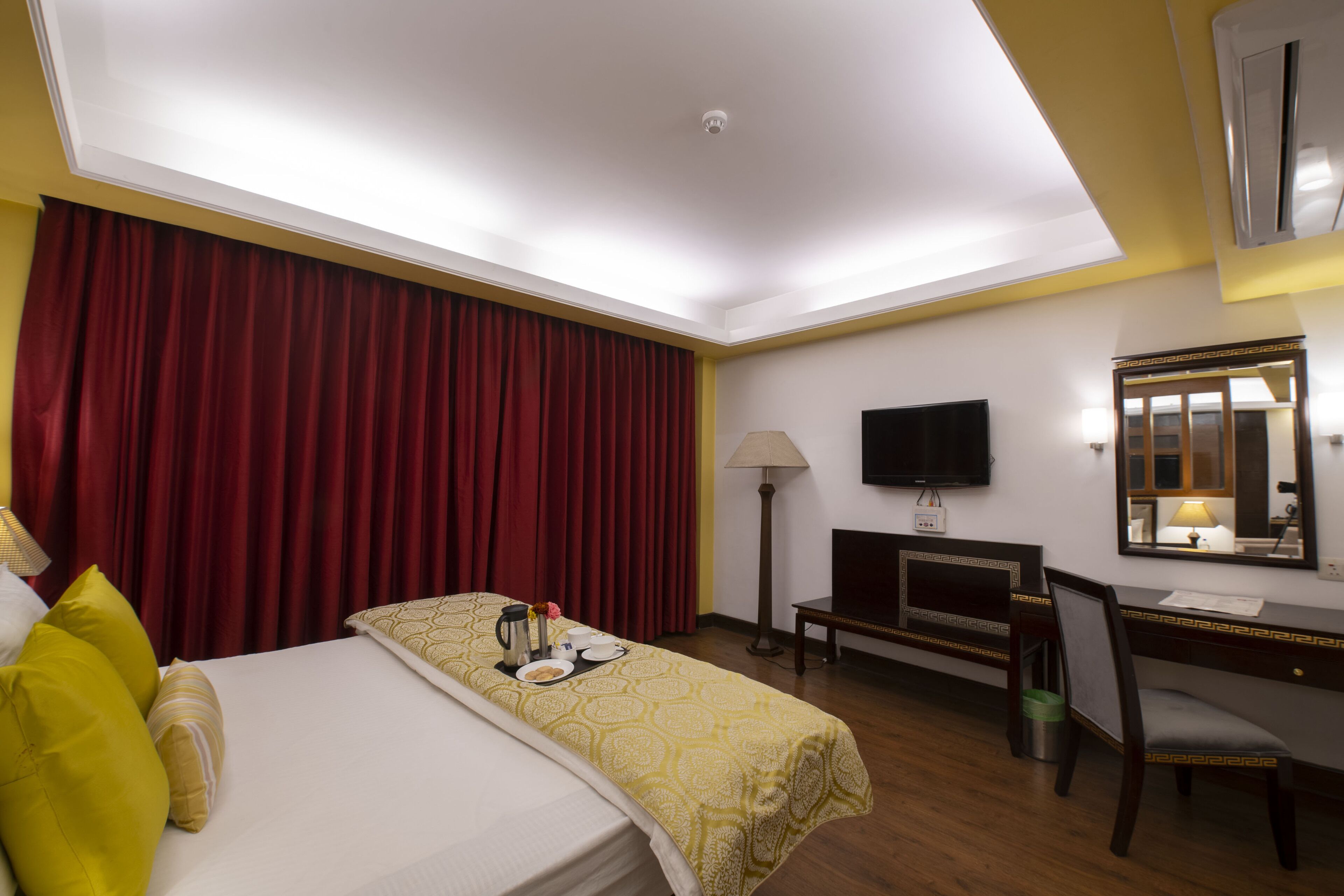 Hotellihuone, jossa on sänky, työpöytä, tuoli, televisio ja peili.