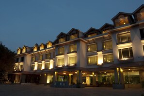 A multi-story hotel with a symmetrical facade, large windows, and a covered entrance area. - Mastiff Grand Manali (Manali)