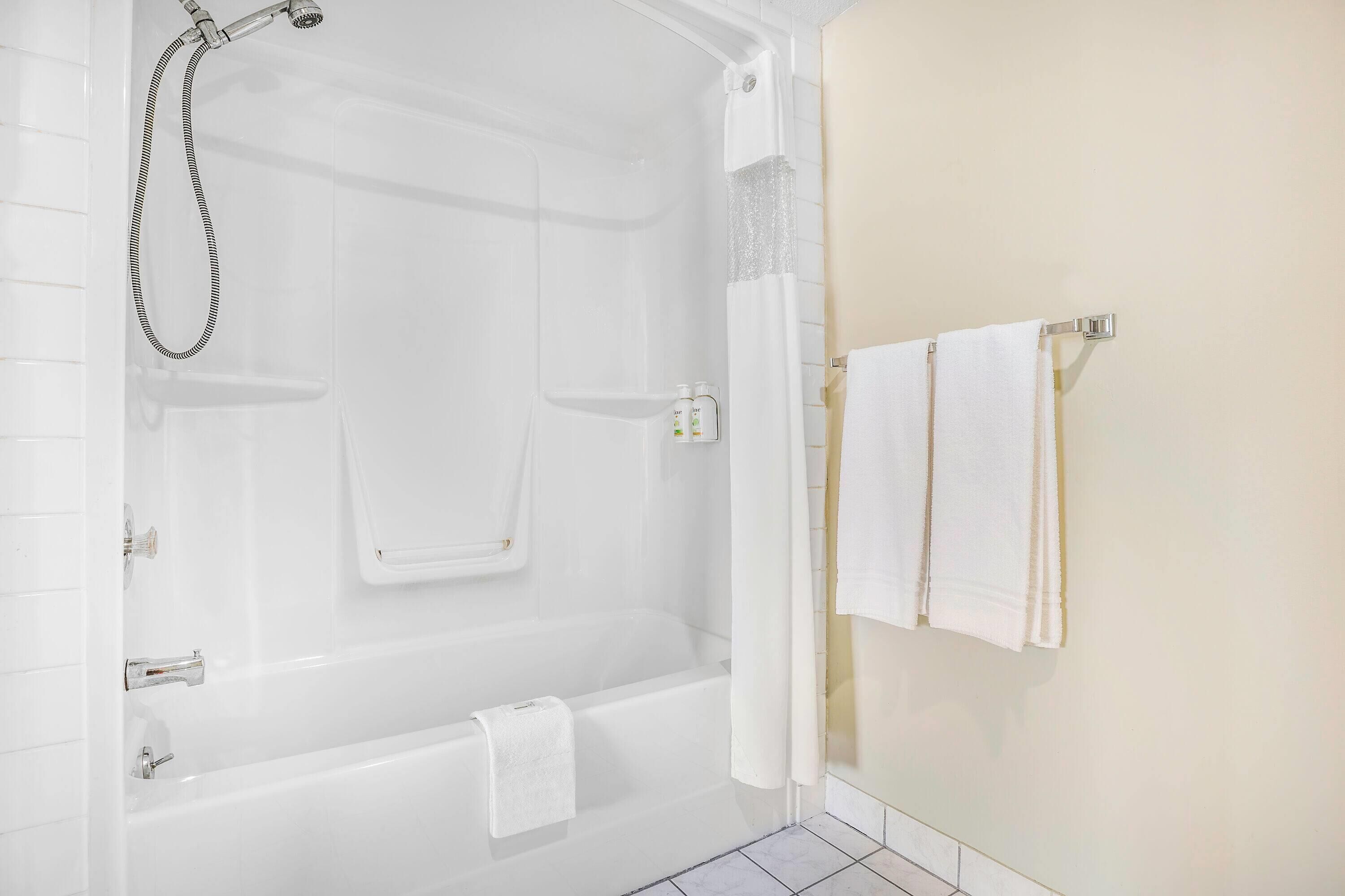 Une salle de bain moderne équipée d’une baignoire, d’une douche et d’un porte-serviettes avec deux serviettes.