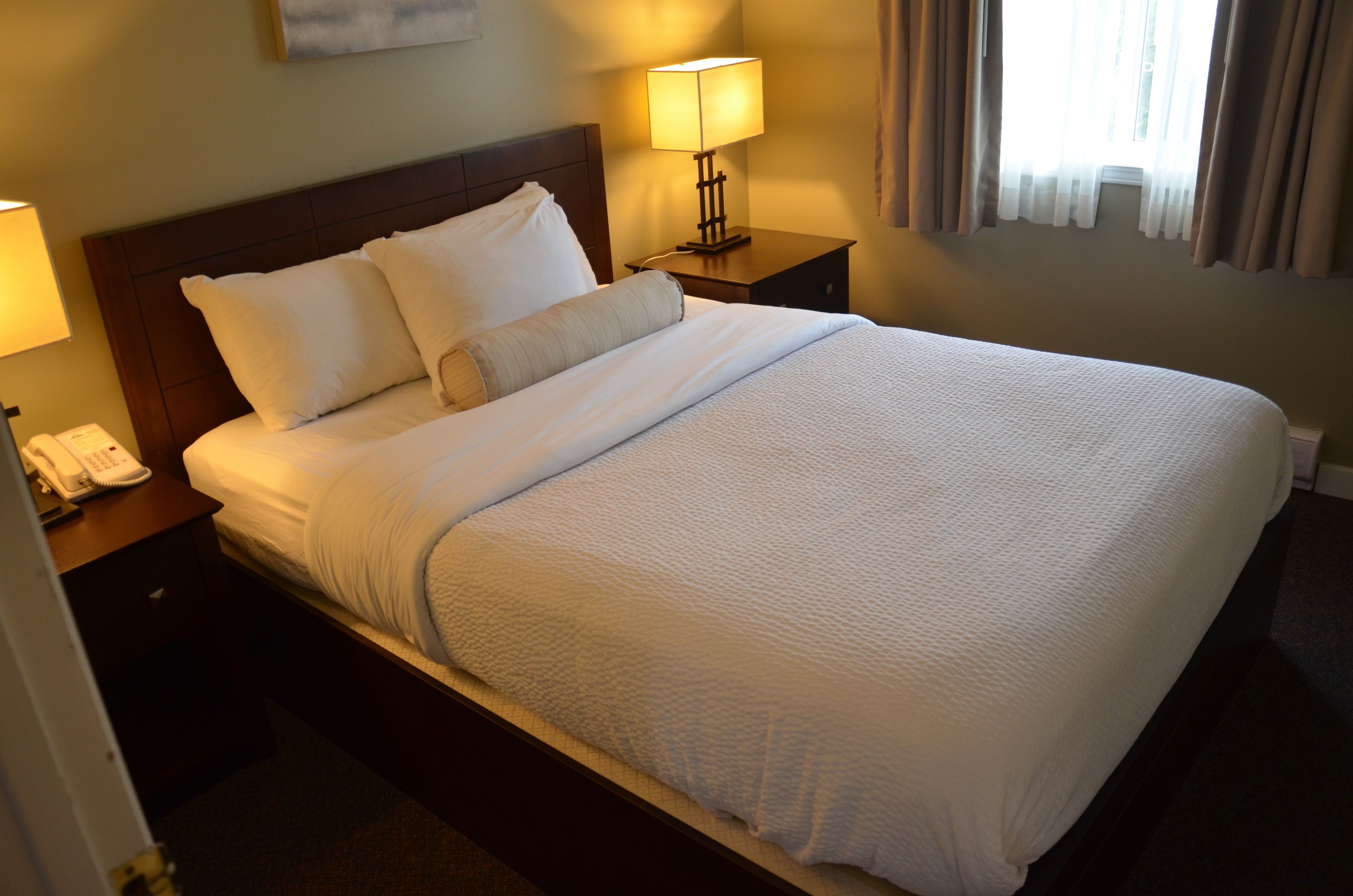 Cama bem arrumada com lençóis brancos em quarto de hotel.