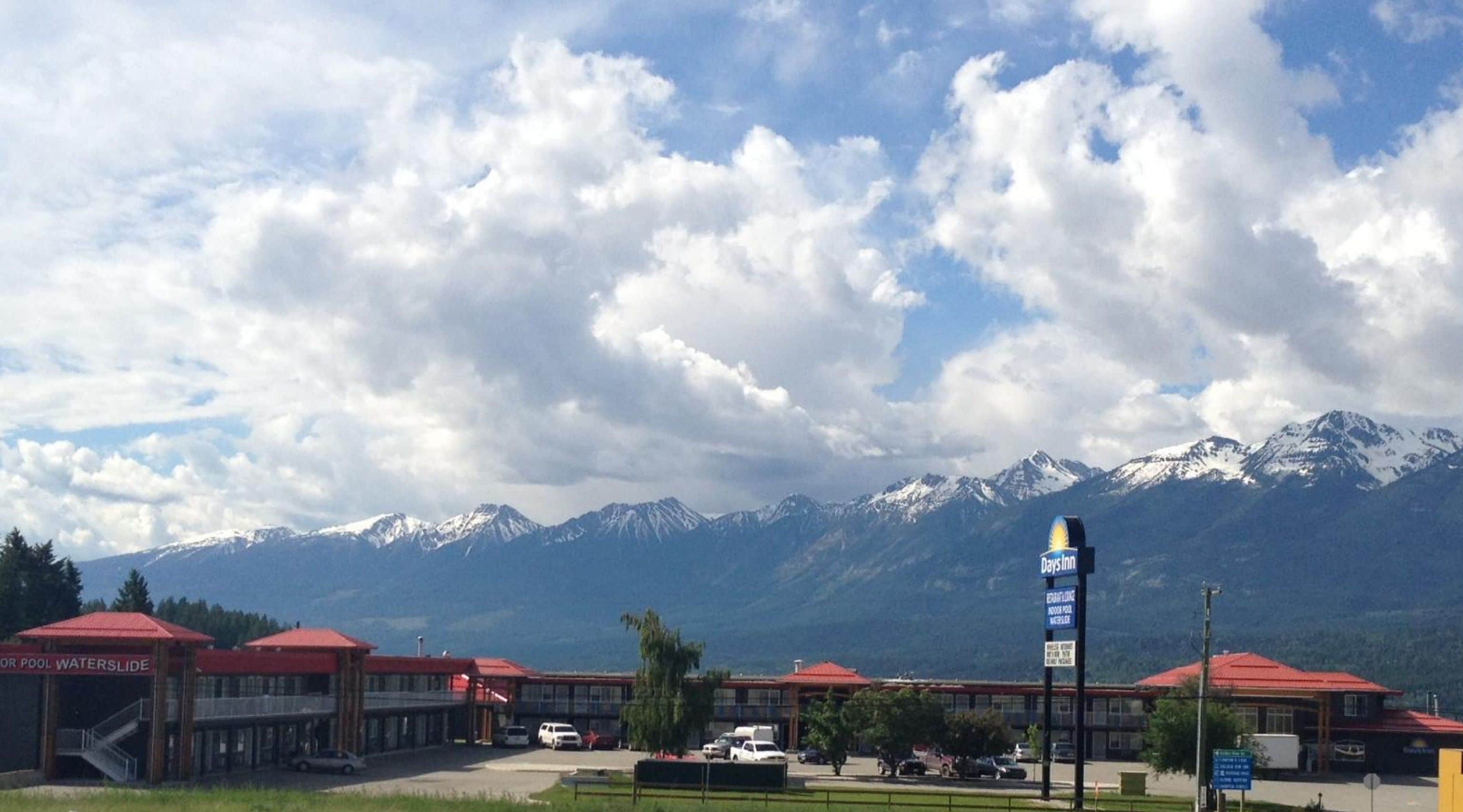 A hotel with a Days Inn sign, a pool, and a mountain backdrop.