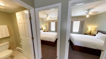 A hotel room with two beds, a bathroom, and a ceiling fan.
