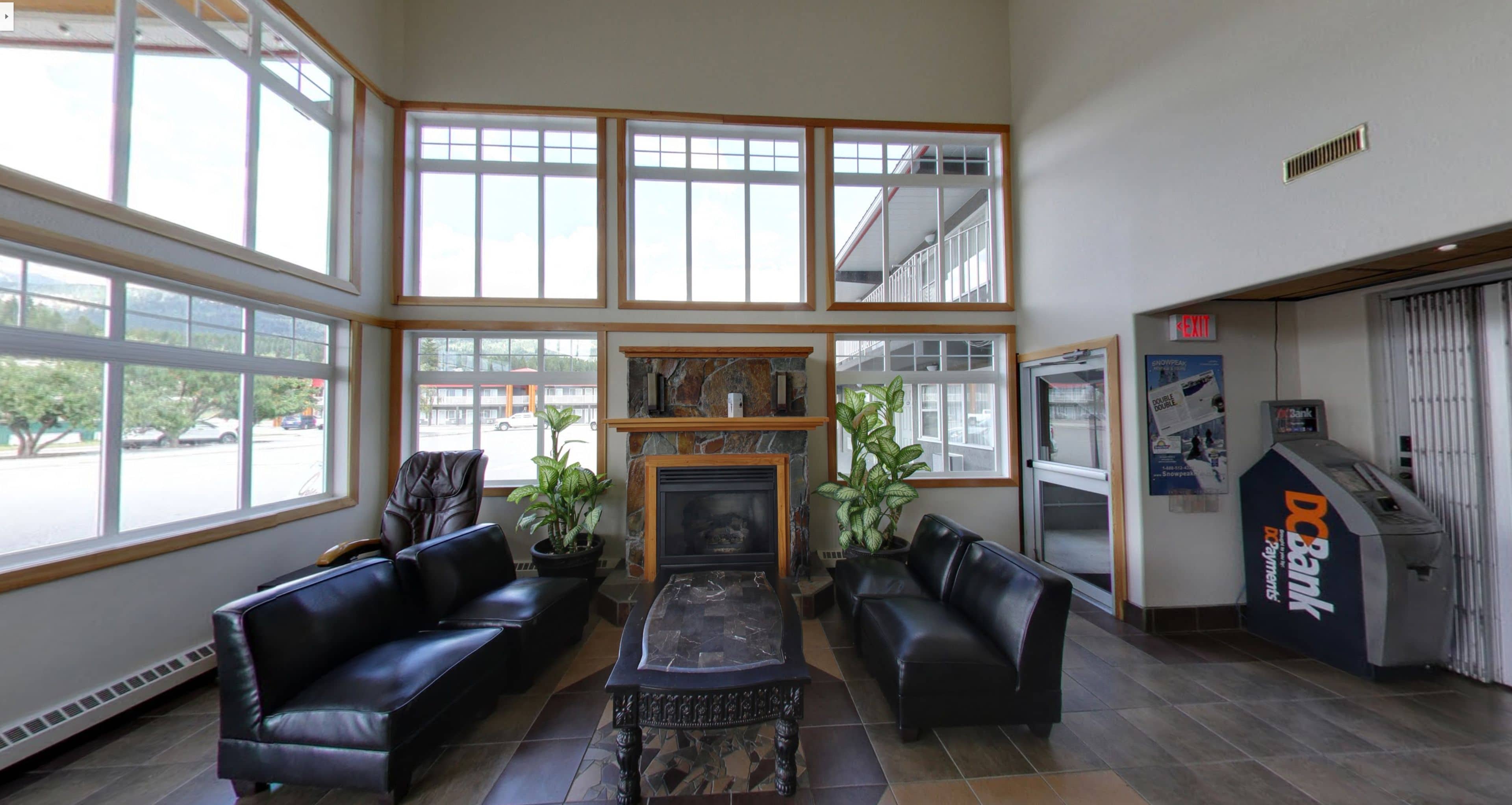 A lobby with a fireplace, leather sofas, and large windows.