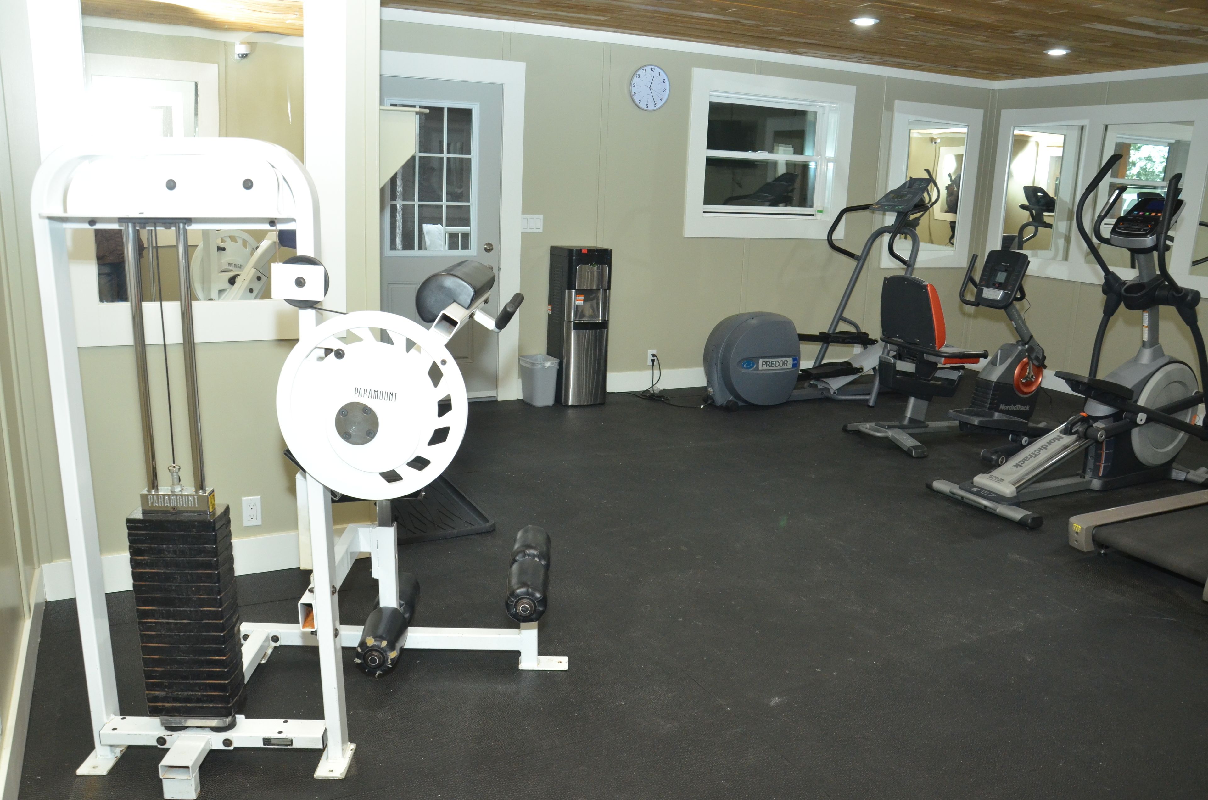 A gym with various exercise equipment including a weight machine, a stationary bike, and an elliptical trainer.