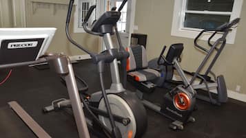 A gym with various exercise equipment including a PRECOR elliptical, a NordicTrack bike, and a treadmill.