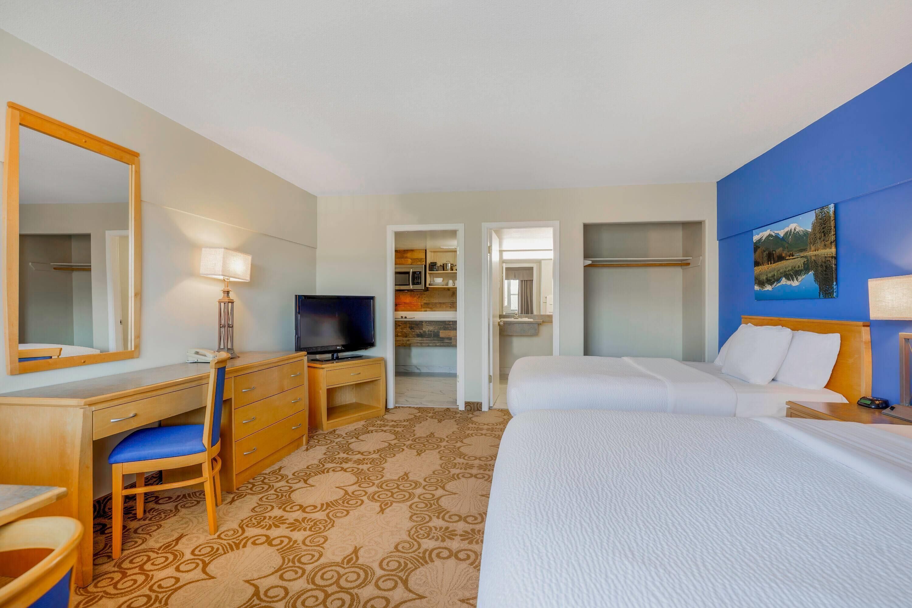 Ein Hotelzimmer mit Bett, Schreibtisch mit Stuhl, Fernseher und angrenzendem Badezimmer.