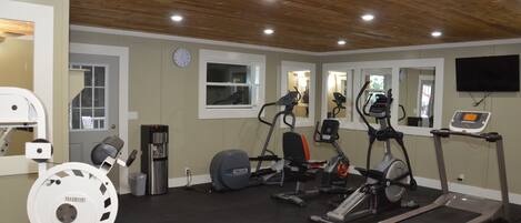A home gym with a treadmill, elliptical, stationary bike, and weight machine.