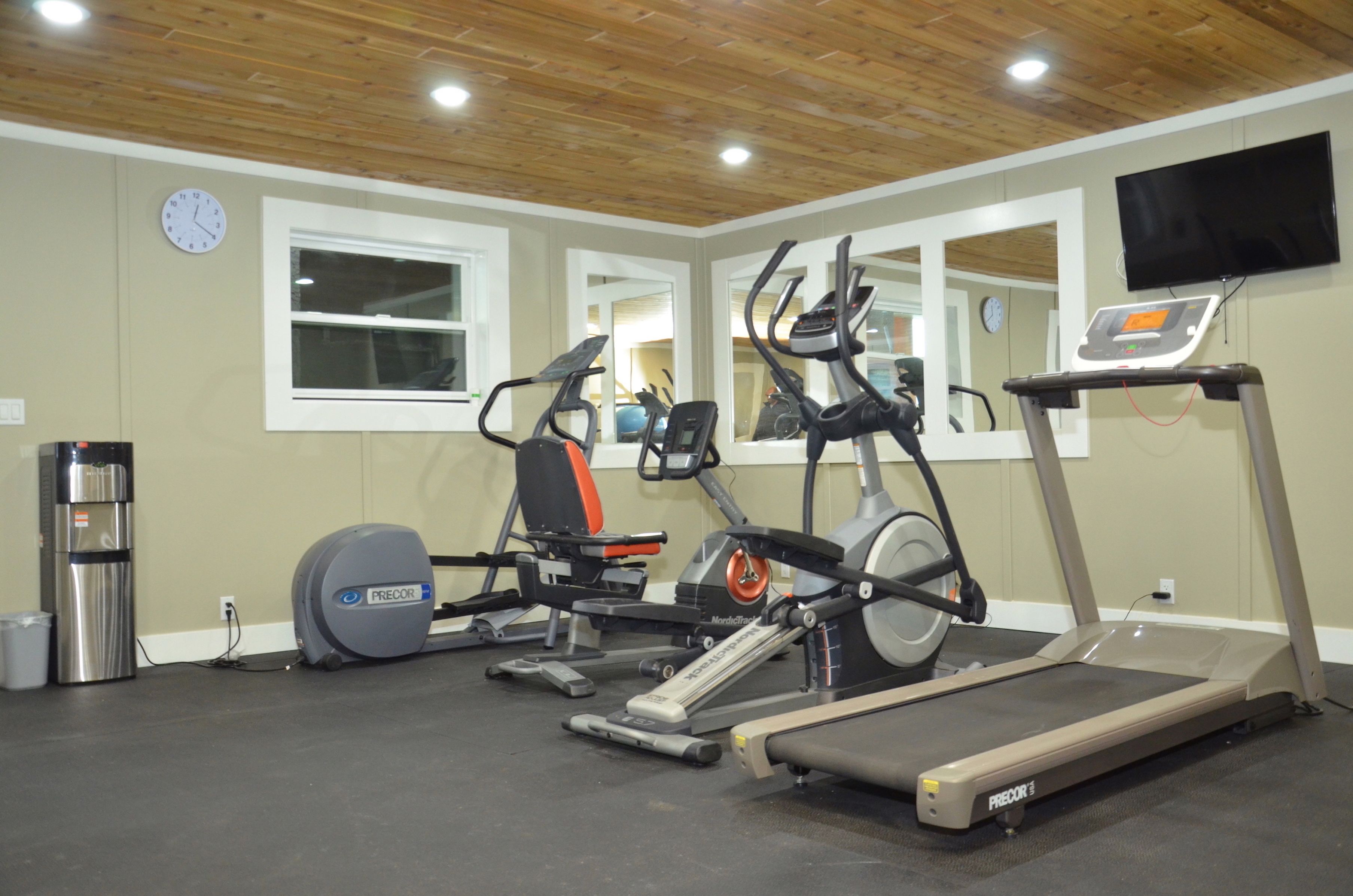 A home gym with a treadmill, elliptical, and stationary bike.