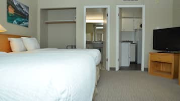 Une chambre d’hôtel comprenant un lit, une télévision, une petite armoire en bois et une kitchenette.