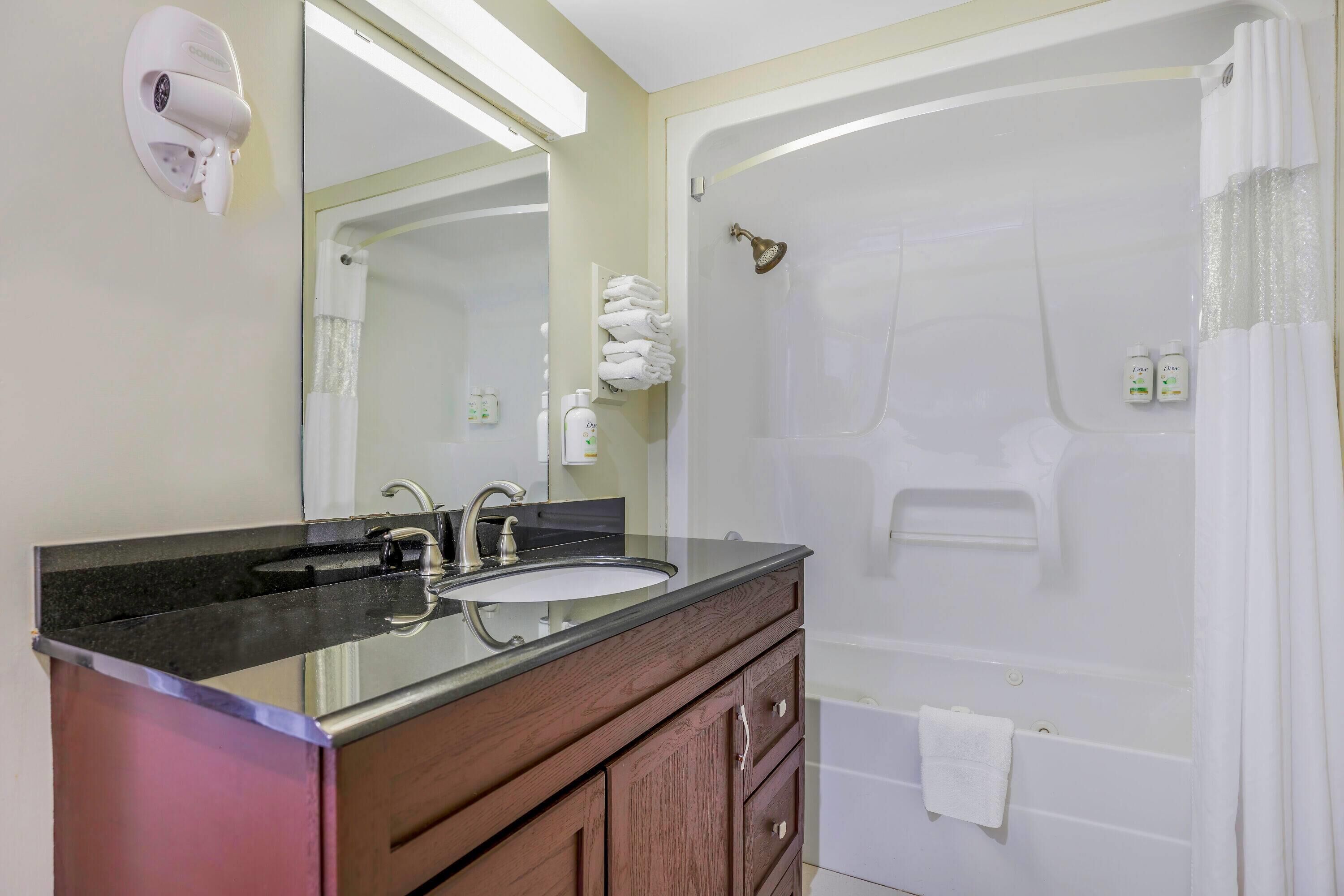 Une salle de bain équipée d’un lavabo, d’un miroir, d’un meuble-lavabo et d’une baignoire avec un rideau de douche.