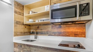 Une cuisine avec un crédence en bois, un évier en acier inoxydable, un four à micro-ondes et une cuisinière intégrée.