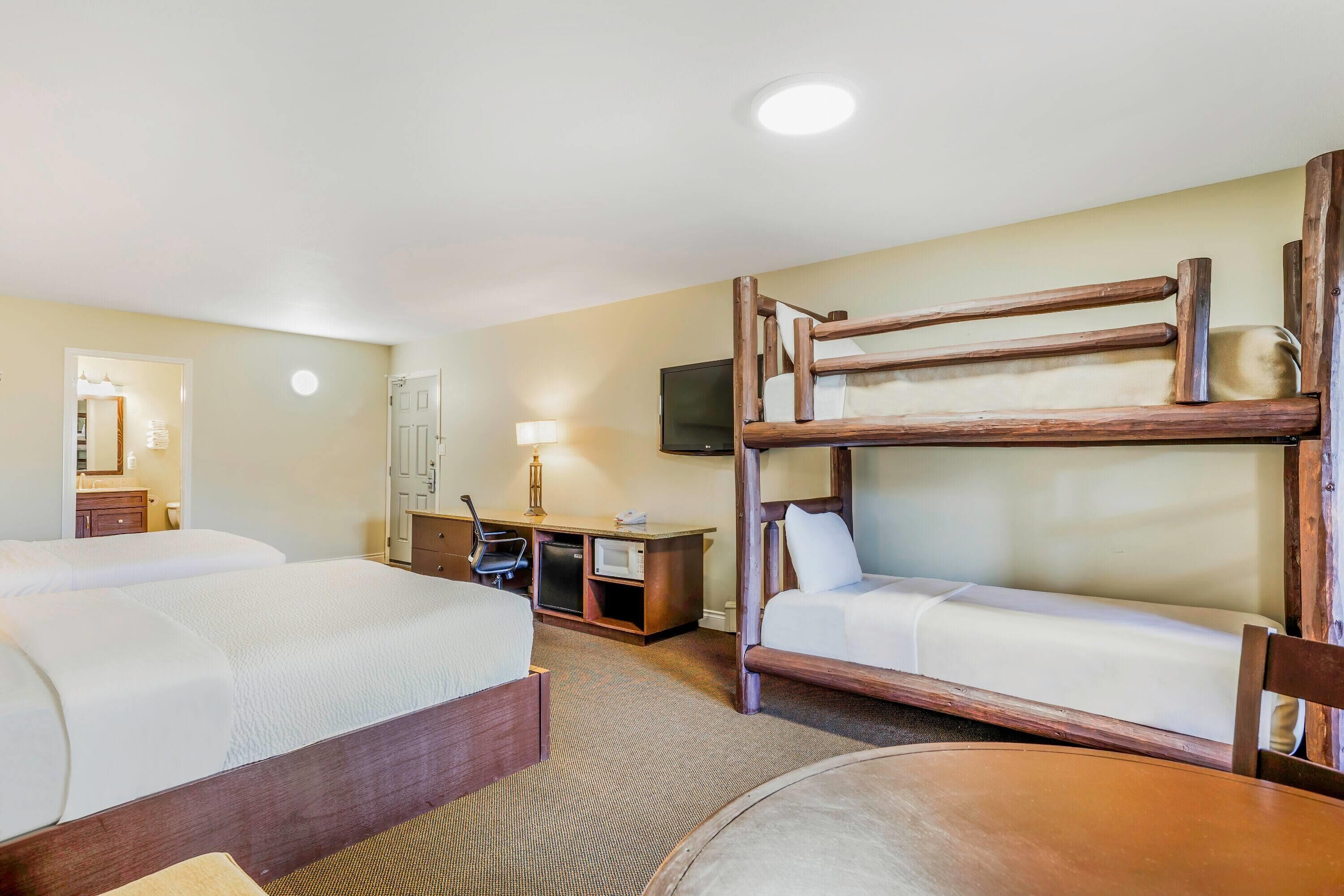 Ein Hotelzimmer mit zwei Betten, einem Schreibtisch, einem Stuhl, einem Fernseher und einem Spiegel.