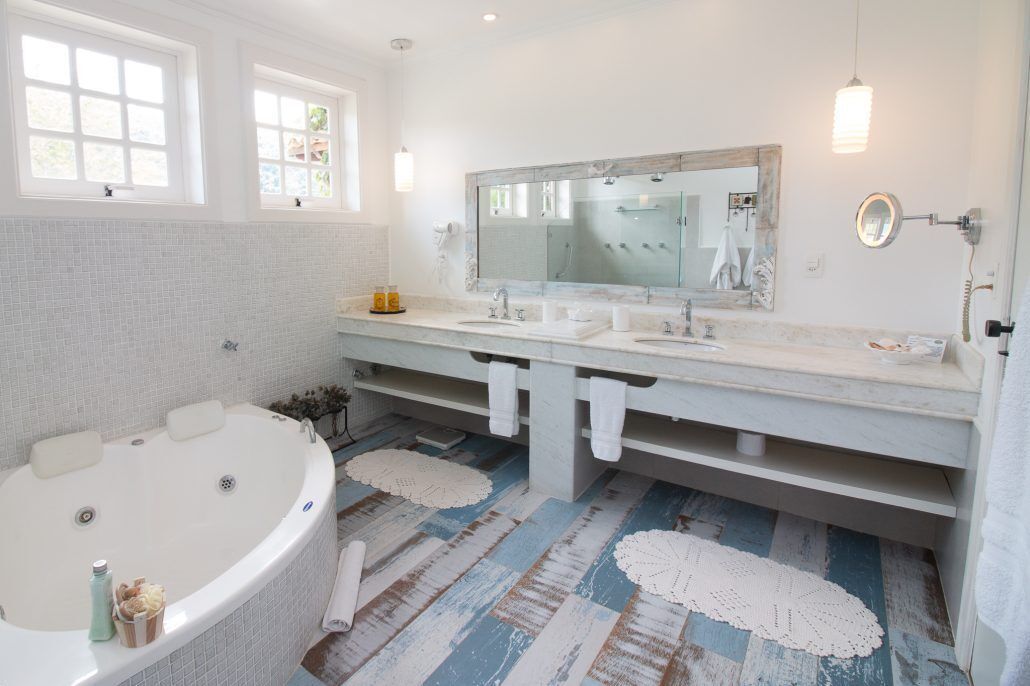 Un baño con una bañera grande, dos lavamanos, un espejo amplio y una zona de ducha.