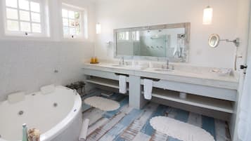 Un baño con una bañera grande, dos lavamanos, un espejo amplio y una zona de ducha.