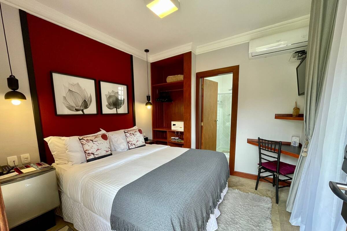Ein ordentlich eingerichtetes Schlafzimmer mit einem Bett, einem Nachttisch und einem Schreibtisch mit Stuhl.