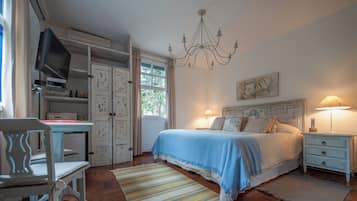 A bedroom with a bed, bedside tables, a TV, and a chandelier.