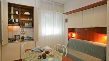 A compact living space with a kitchenette, dining area, and a sofa.