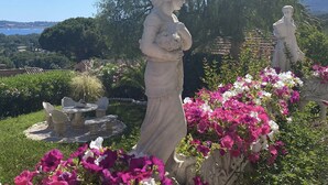 A garden with statues, a table, and chairs.