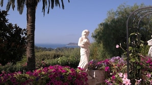 A statue in a garden with a view of the sea.