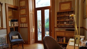 A room with wooden floors, a desk with a lamp, a chair, a bookshelf, and a door leading to an outdoor area. - Lauderville Guest House (Edinburgh)
