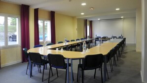 A conference room with a long table, chairs, and a projector screen. - The Originals City, Hôtel des Arènes, Saintes (Saintes)