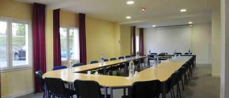 A conference room with a long table, chairs, and a projector screen.