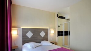 A hotel room with a bed, two bedside lamps, a nightstand, a mirror, and a shower area. - The Originals City, Hôtel des Arènes, Saintes (Saintes)