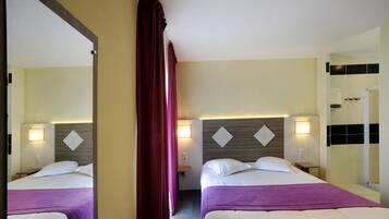 Habitación de hotel con dos camas, un espejo grande y vista al baño.