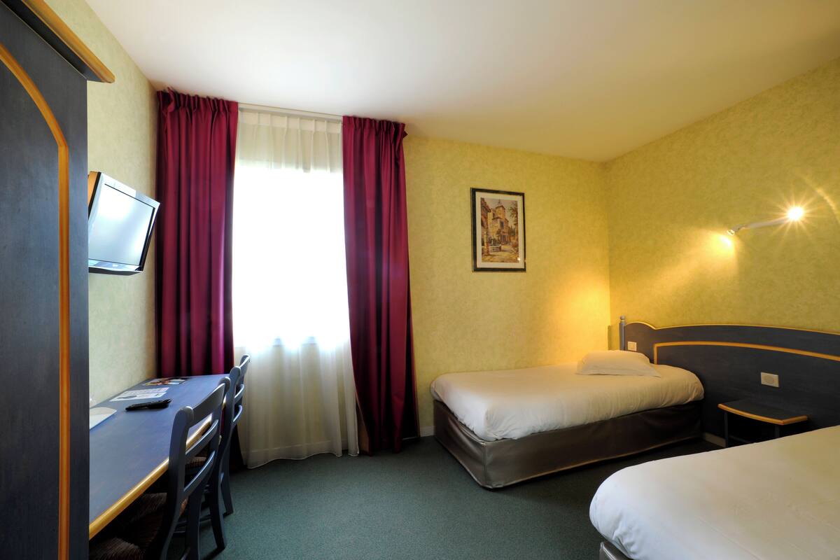 A hotel room with a bed, a desk, and a television.