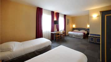 Habitación de hotel con dos camas individuales, un escritorio con silla, televisión y una mesita.