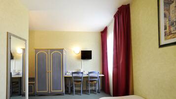Habitación de hotel con dos camas, un escritorio con silla, armario, televisor y un cuadro en la pared.