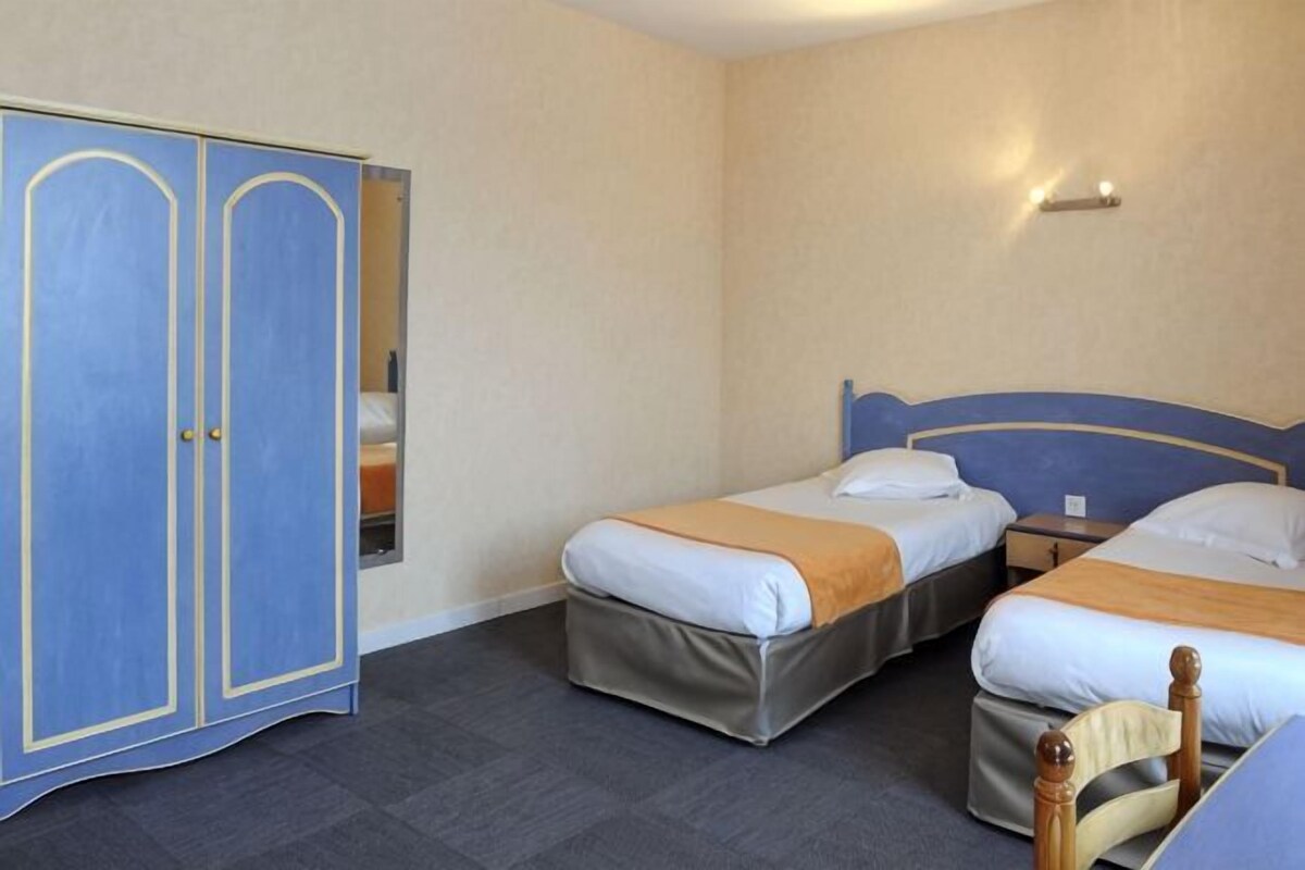 Een kamer met twee eenpersoonsbedden, een garderobe en een nachtkastje.