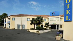 A hotel with a reception area, a sign indicating the location of the reception, and a parking lot. - The Originals City, Hôtel des Arènes, Saintes (Saintes)
