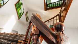 A wooden staircase with a handrail and a view of a room with a window and a door in the background. -  Hotel Mirabeau (Tours)