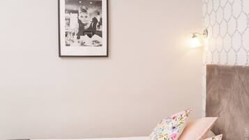 A bedroom with a bed, a framed photo on the wall, and a wall-mounted light fixture.