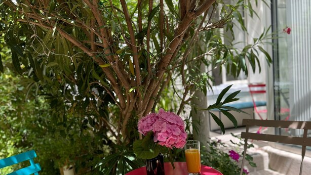 A red table with a glass of orange juice, a small cake, and a pink flower. -  Hotel Mirabeau (Tours)