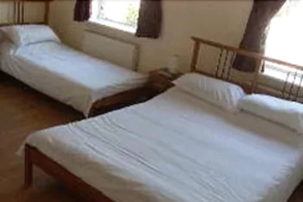 Two single beds with wooden frames in a room with a tiled floor.